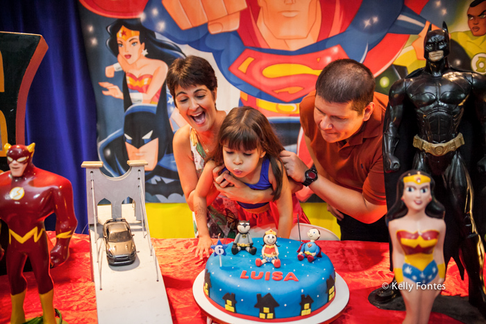 fotos festa infantil rj - bolo mulher maravilha super heróis parabéns assoprando as velas menina Luisa com os pais feliz aniversário família