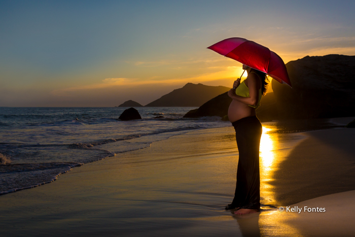 book gestante na praia RJ Dani grávida do Bruno sombrinha vermelha na areia do mar