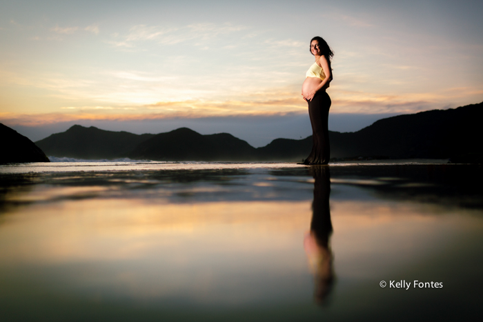 book gestante na areia da praia RJ Dani grávida do Bruno reflexo do sol na água do mar